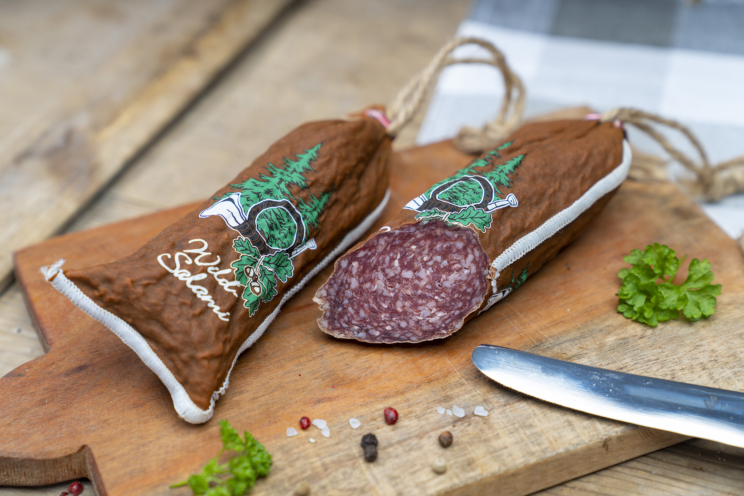 Hirschsalami auf Holzbrett mit Gewürzdeko.