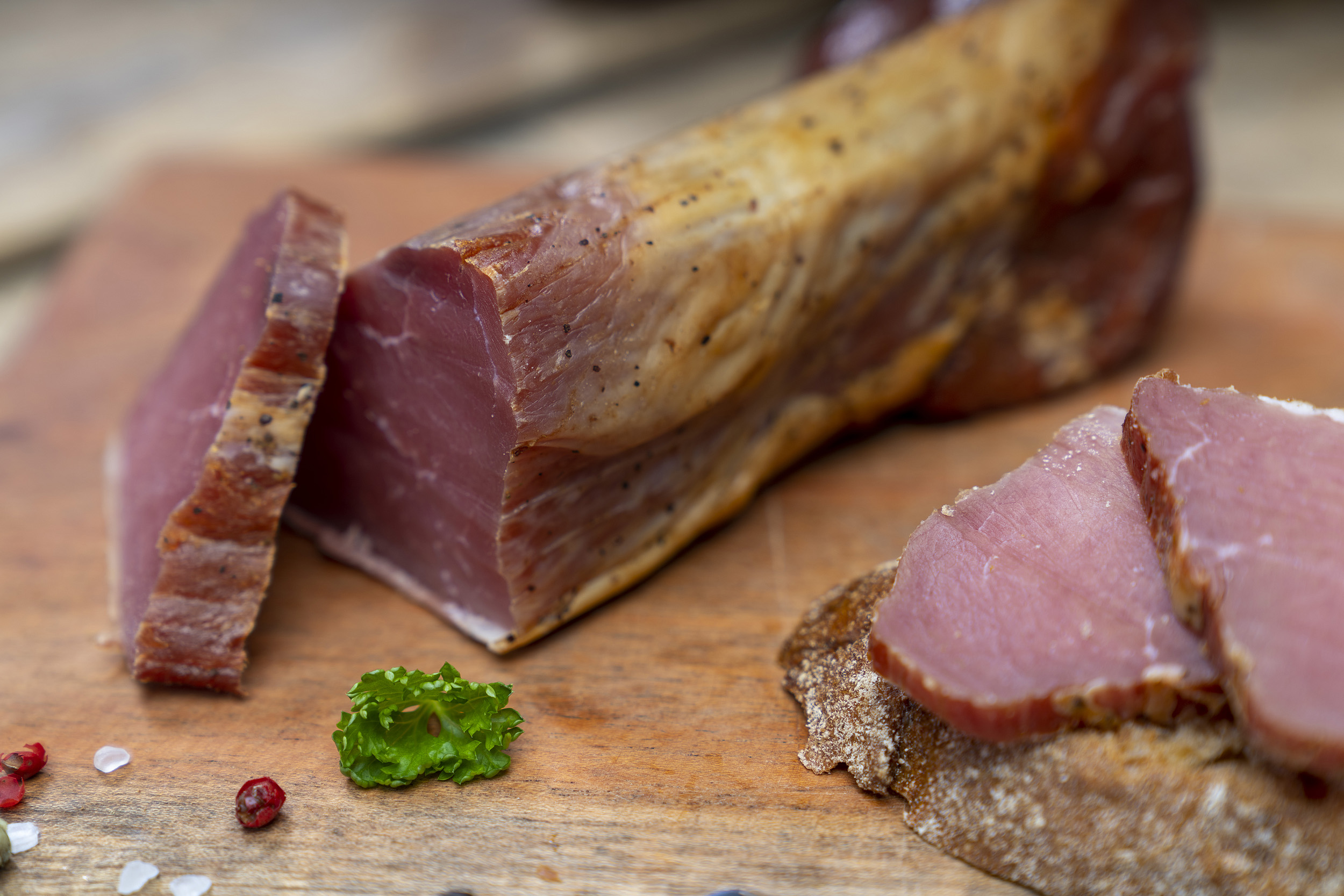 Ein Stück Schinkenfilet der Fleischerei Fessel. Daneben ein Brot mit Schinken.