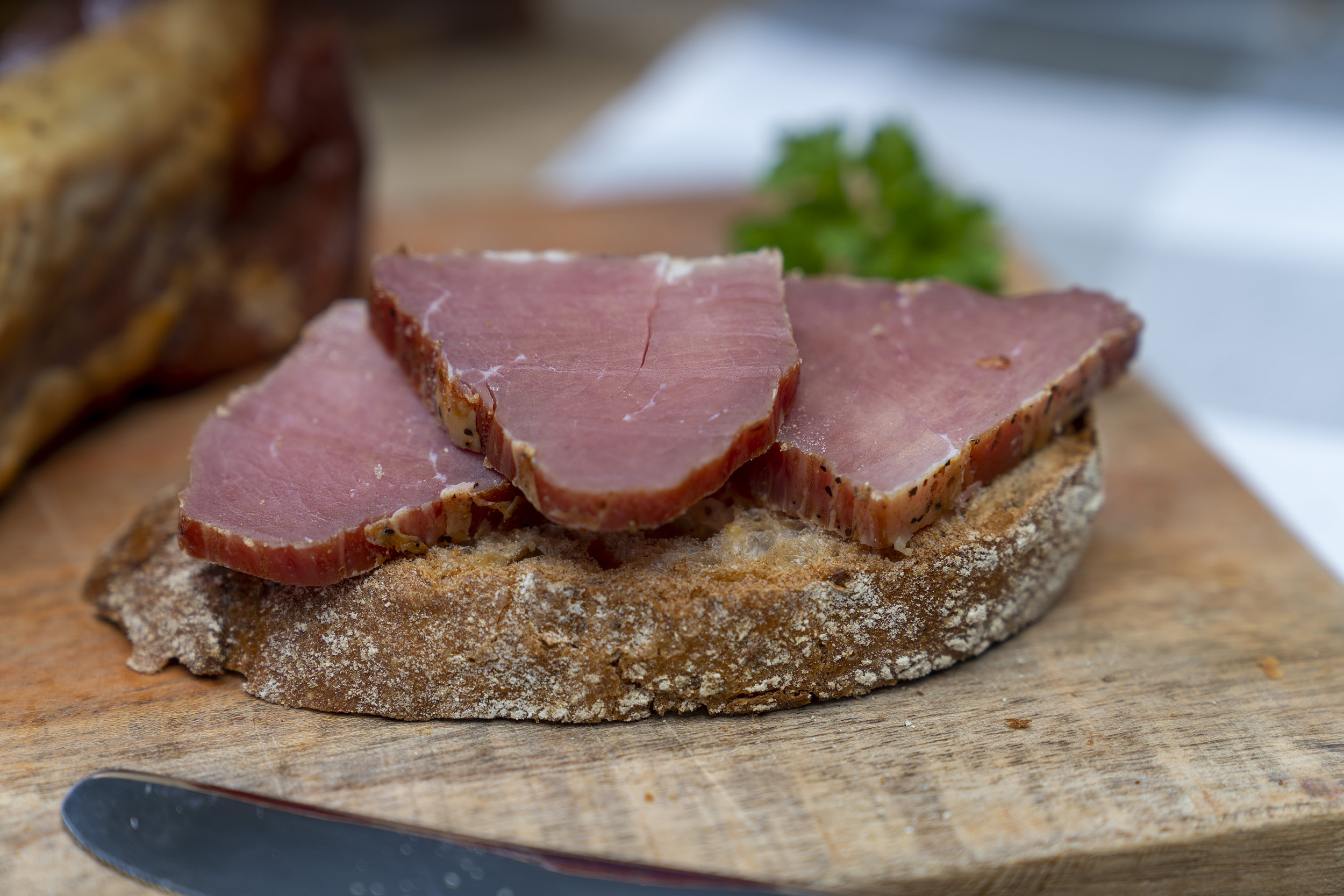Ein Stück Schinkenfilet der Fleischerei Fessel. Daneben ein Brot mit Schinken.