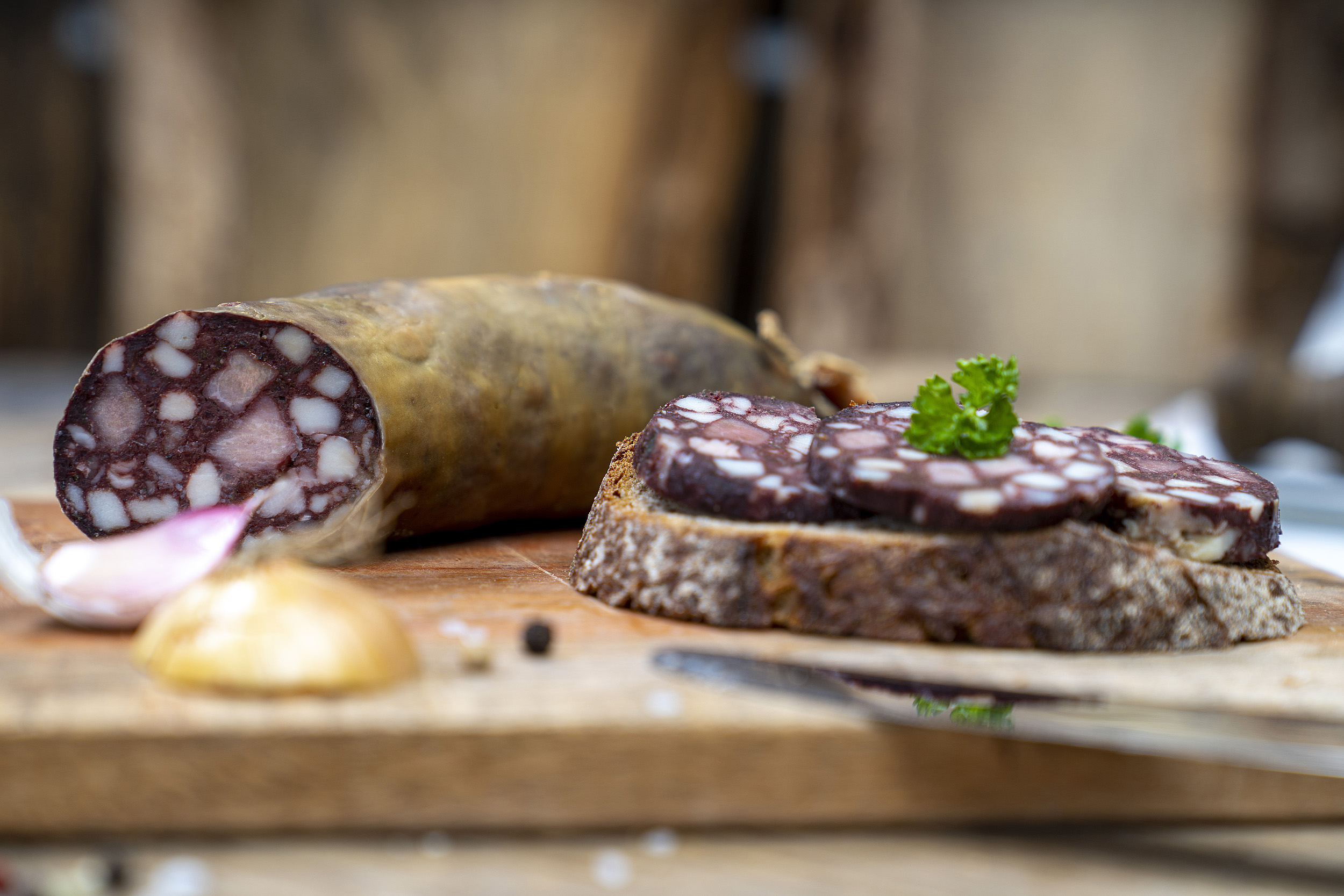 Eine Scheibe Brot mit Rotwurst Scheiben. Auf dem Brett Kräuter, Zwiebeln und die Wurst.