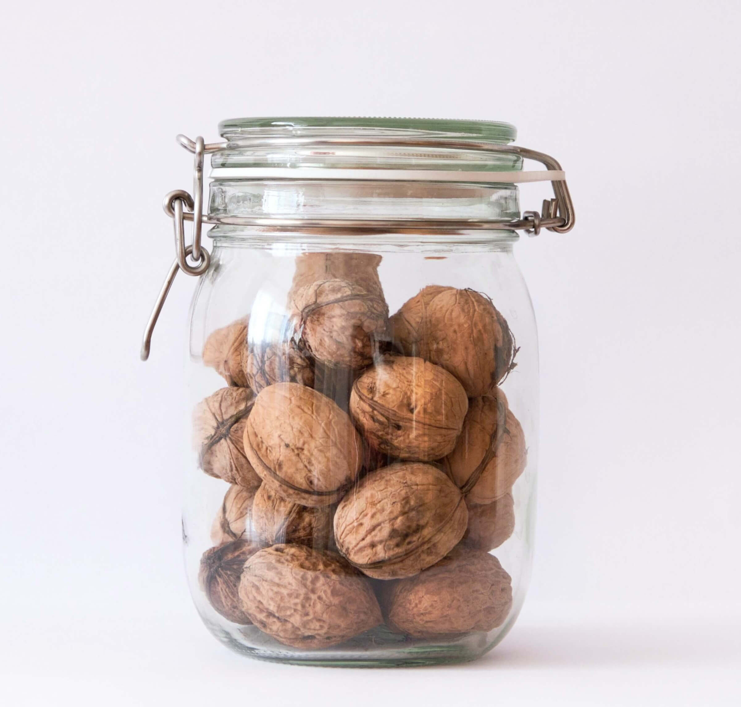 Ein Glas mit Walnüssen auf weißem Untergrund.
