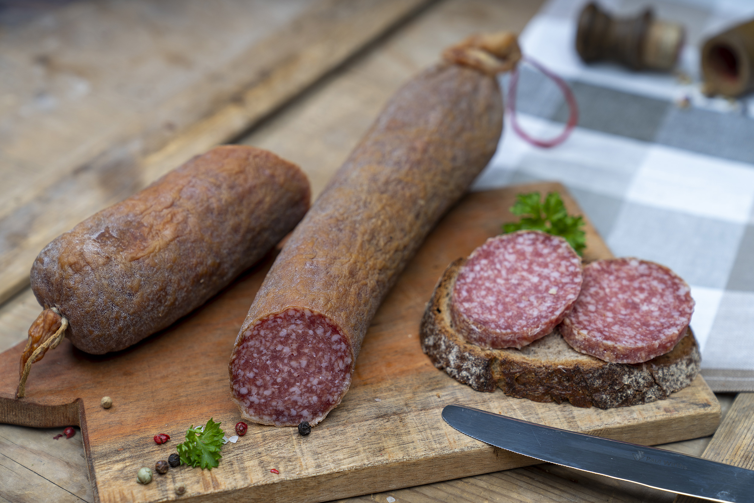 Aufgeschnittene Schlackwurst auf einem Brett. Daneben ein Brot mit der Wurst.