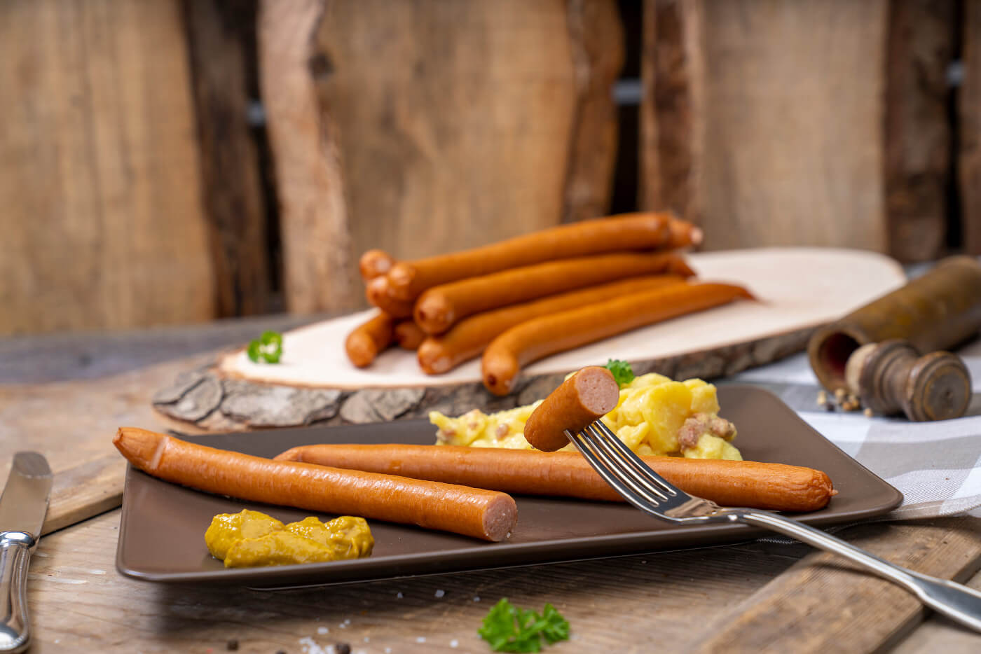 Zwei Wienerwürstchen, Kartoffelsalat und Senf. Hinten weitere Wiener der Fleischerei Fessel.