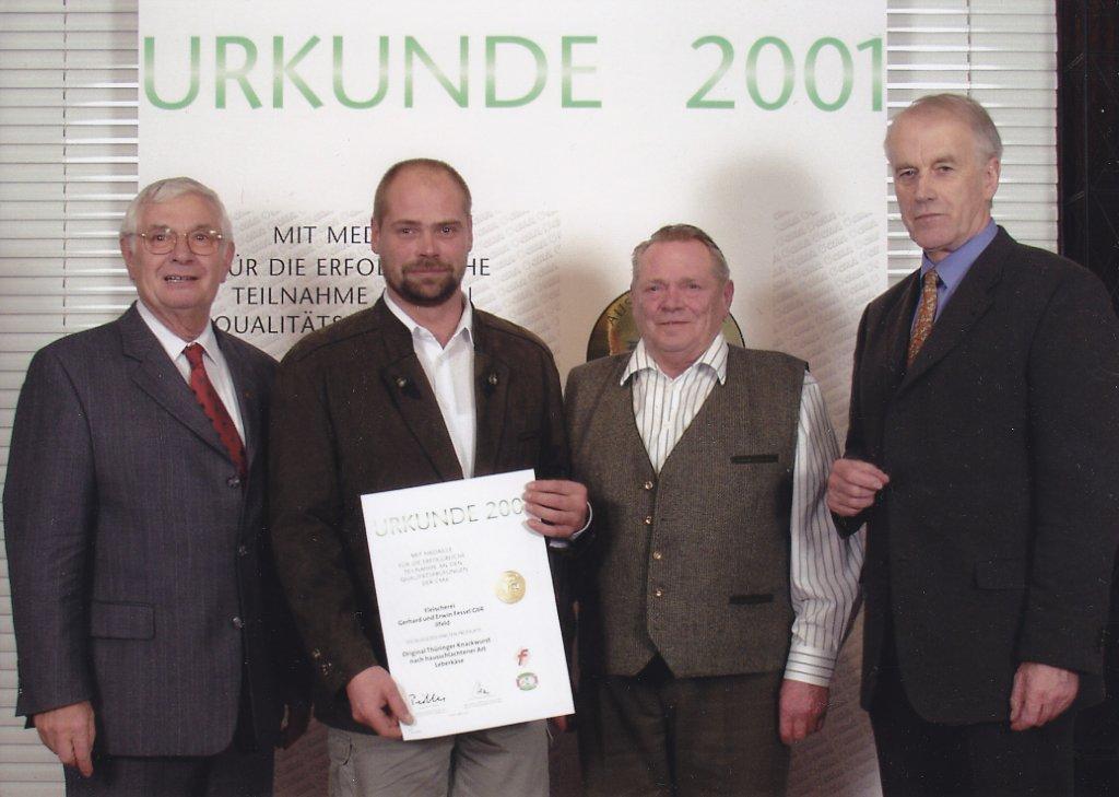 Erwin und Gerhard Fessel bekommen eine Urkunde. Sie stehen vor einem Aufsteller mit dem Titel Urkunde 2001.