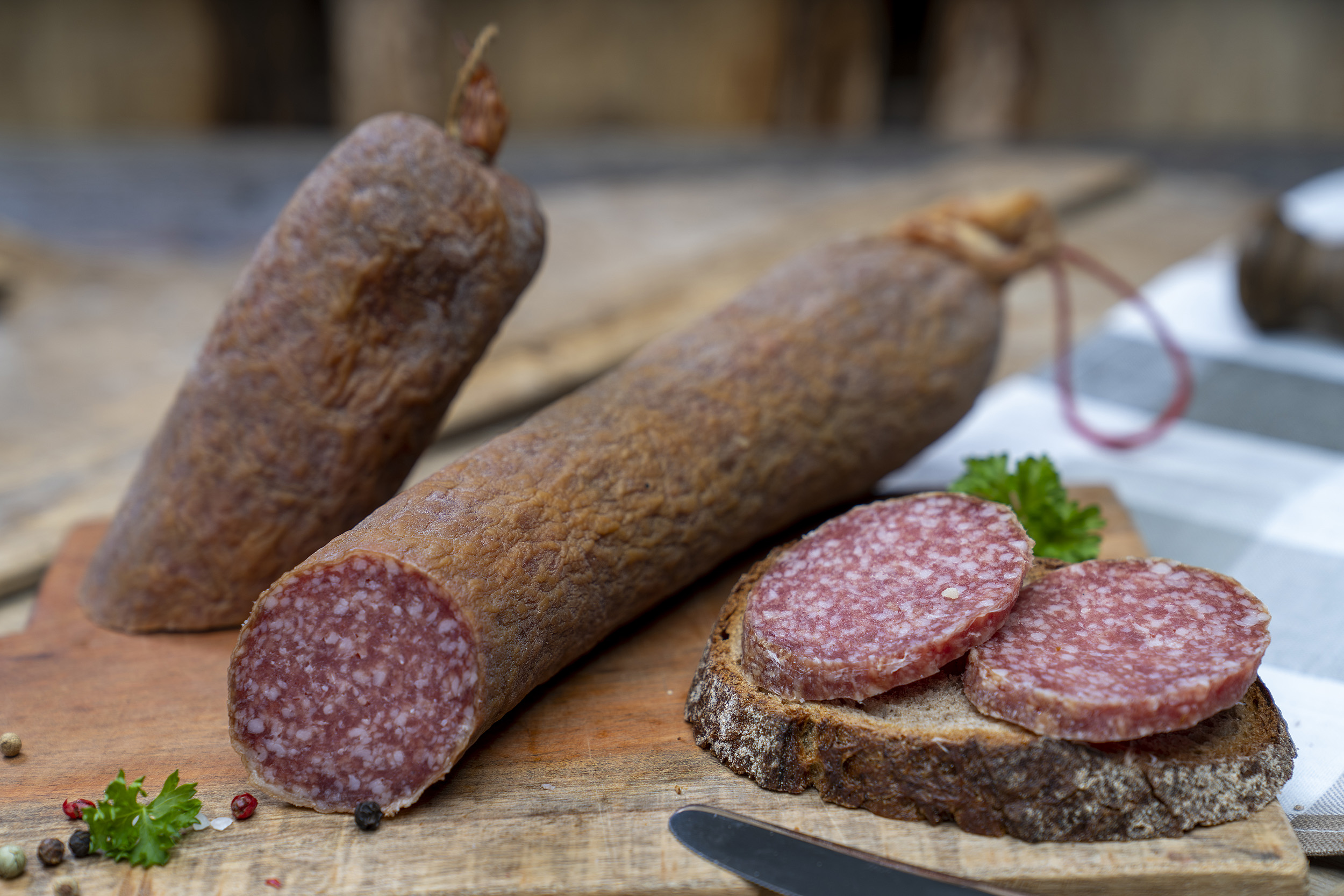Aufgeschnittene Schlackwurst auf einem Brett. Daneben ein Brot mit der Wurst.