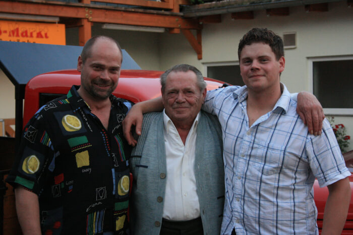 Erwin, Gerhard und Hendrik Fessel Arm in Arm. Im Hintergrund der Hof der Fleischerei und der rote Framo.