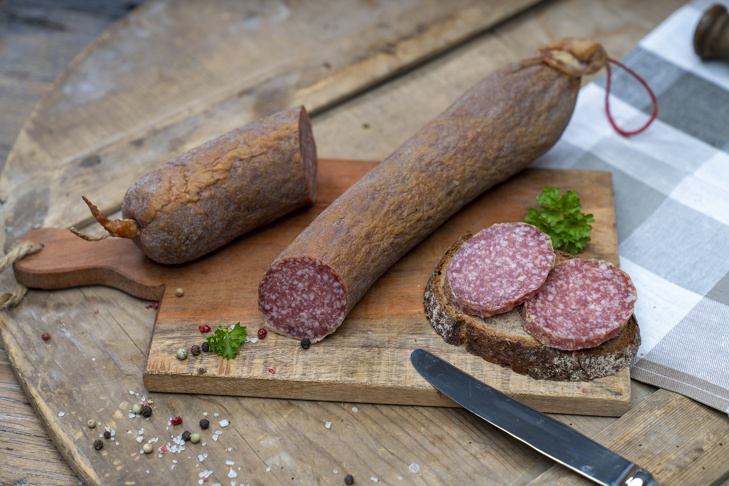 Aufgeschnittene Schlackwurst auf einem Brett. Daneben ein Brot mit der Wurst.