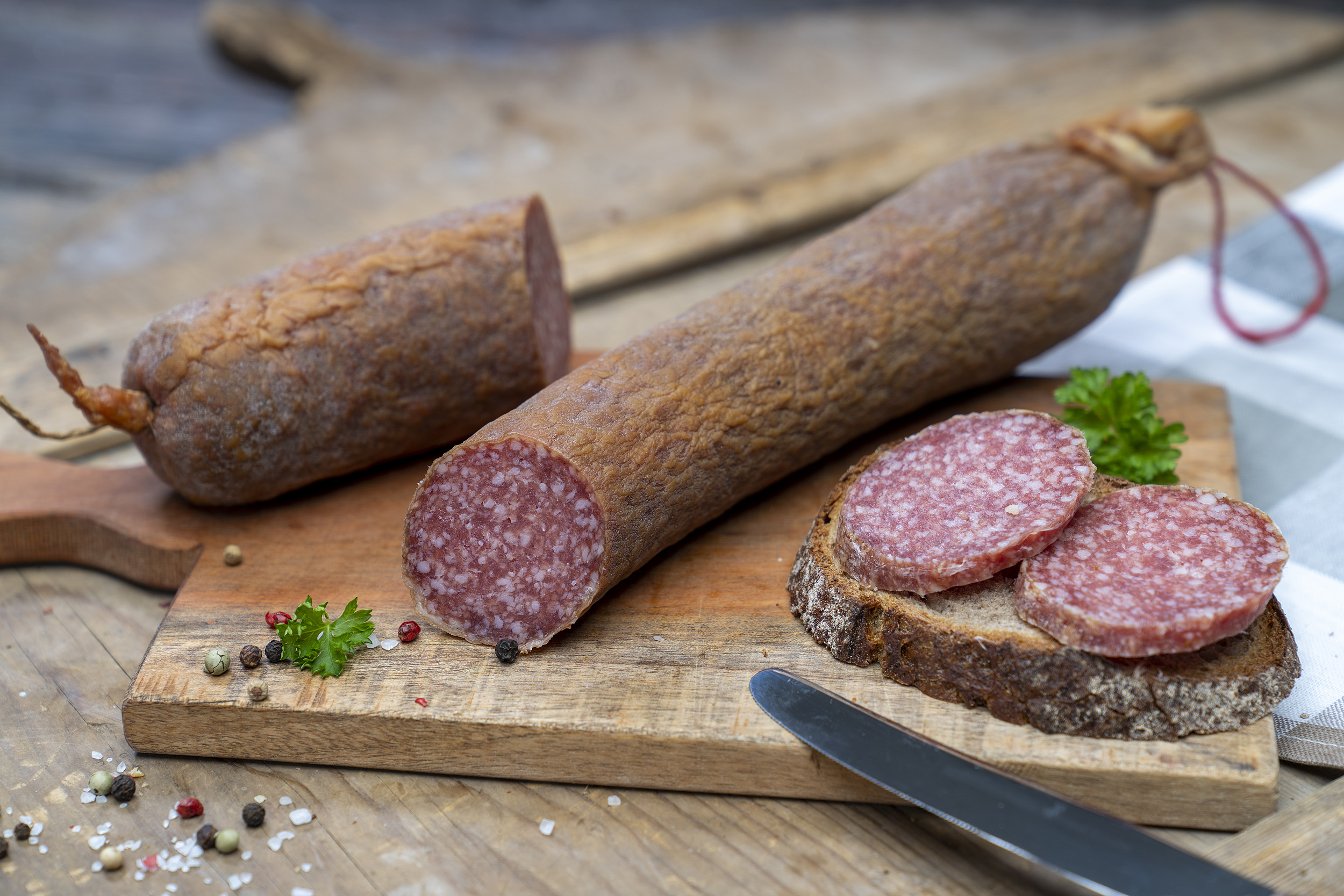 Aufgeschnittene Schlackwurst auf einem Brett. Daneben ein Brot mit der Wurst.