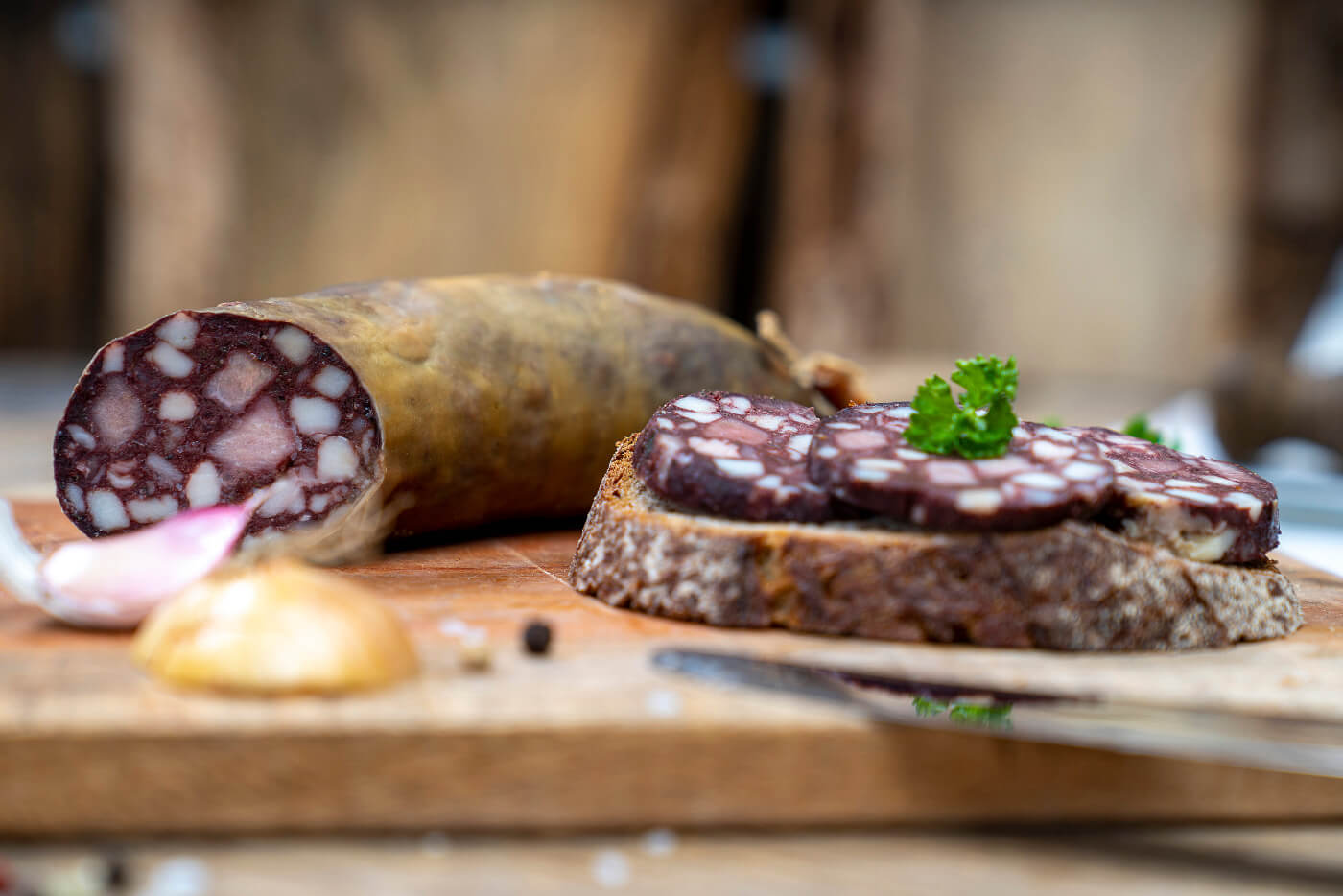 Eine Scheibe Brot mit Rotwurst Scheiben. Auf dem Brett Kräuter, Zwiebeln und die Wurst.