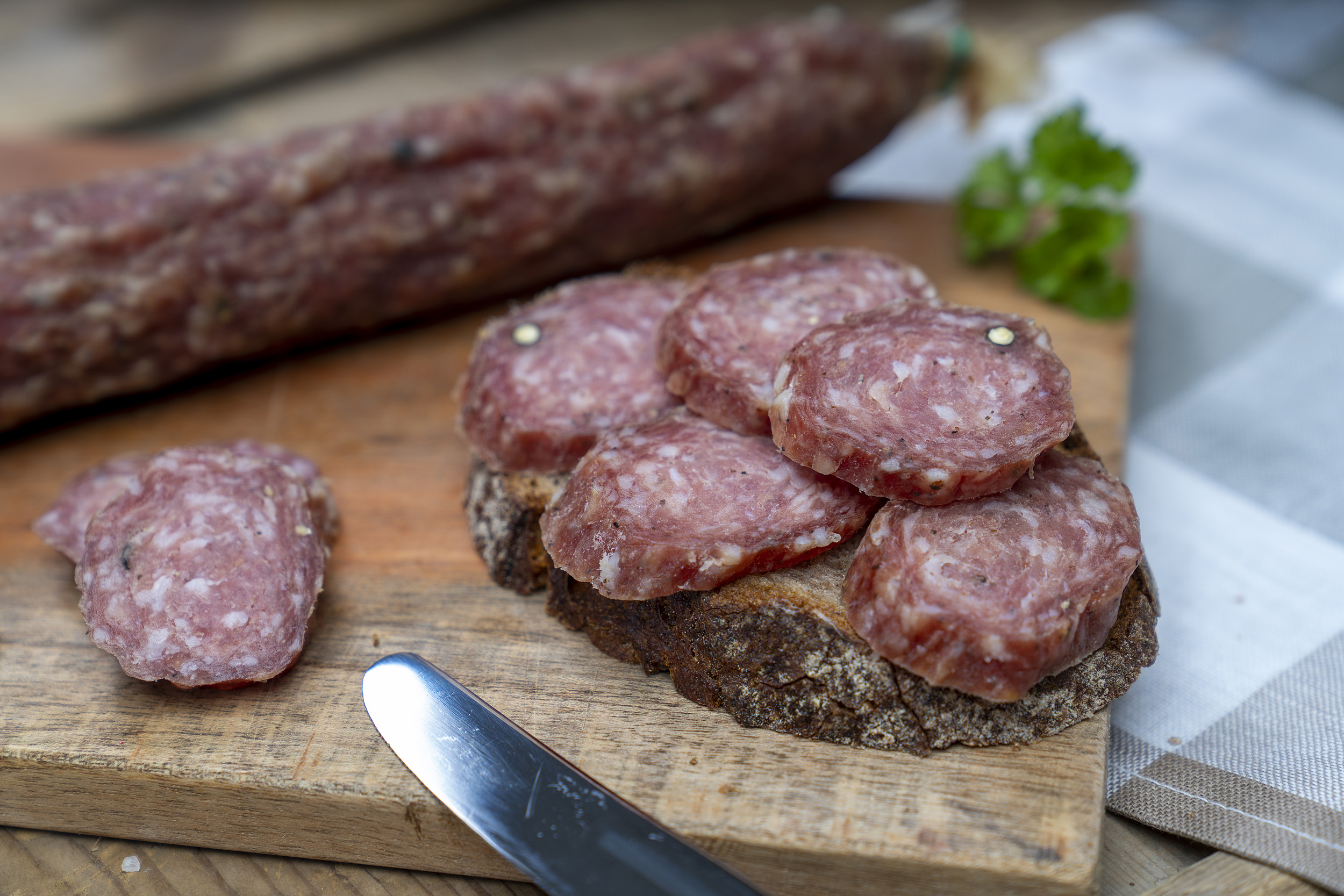 Stracke auf einem Brett. Daneben eine Scheibe Brot mit der Eichsfelder Stracke und Kräuter.