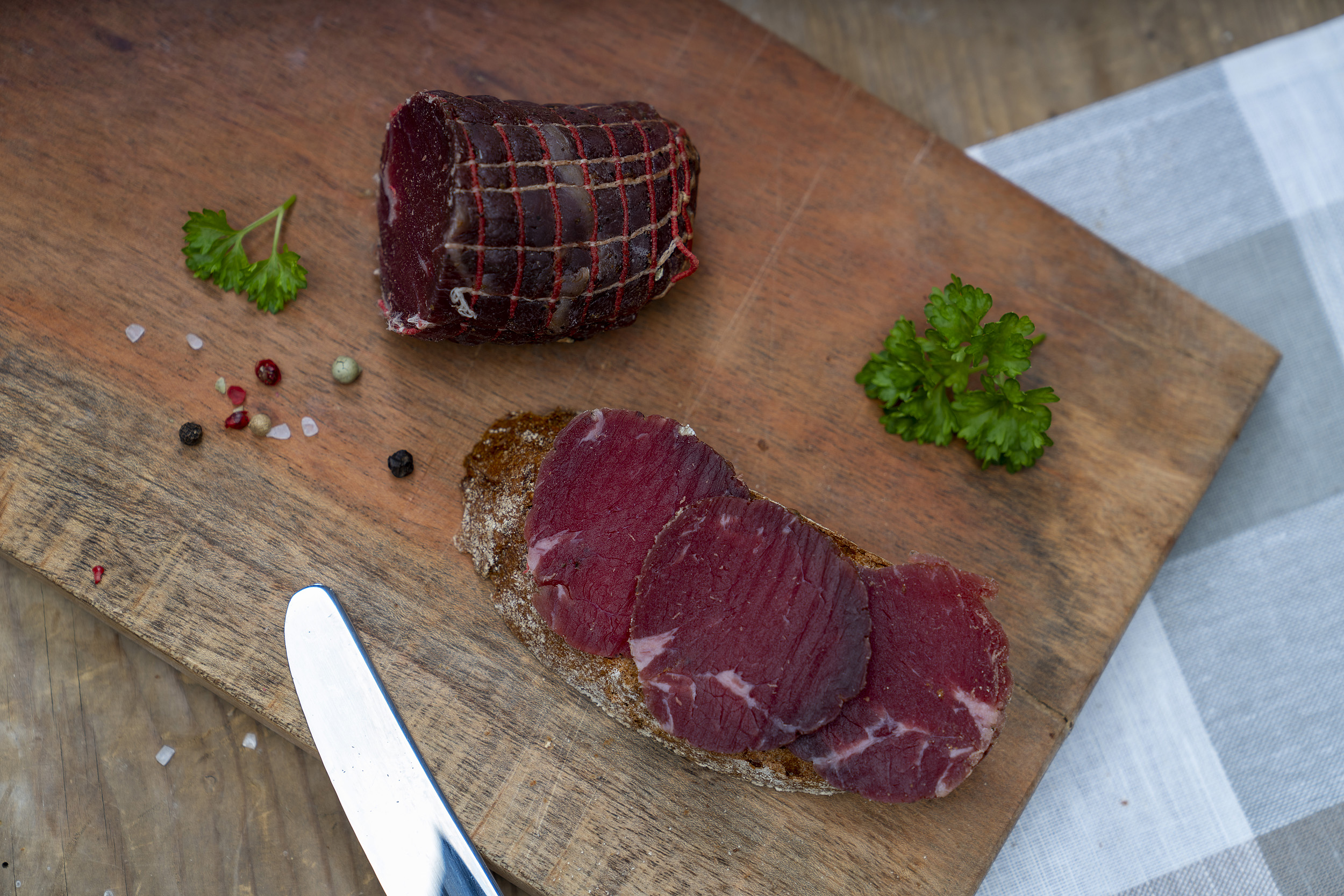 Ein Brot mit Rinderschinken. Auch auf dem Brett das Schinkenstück und Petersilie.