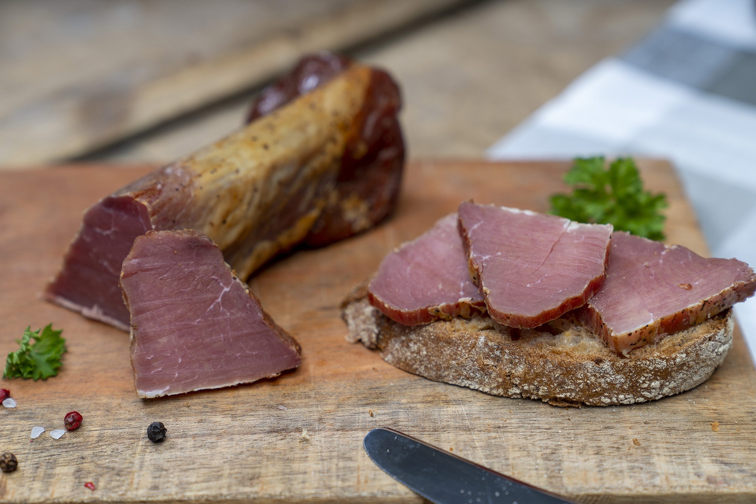 Ein Stück Schinkenfilet der Fleischerei Fessel. Daneben ein Brot mit Schinken.